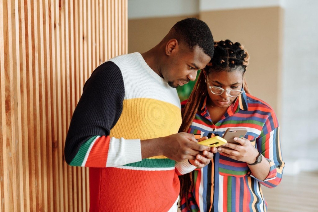 Homem e mulher olhando para a tela de um celular.